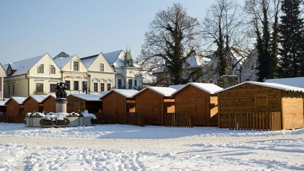 Žilina sa prebúdza do zimného rána, keď zasnežené stánky čakajú na začiatok vianočných trhov